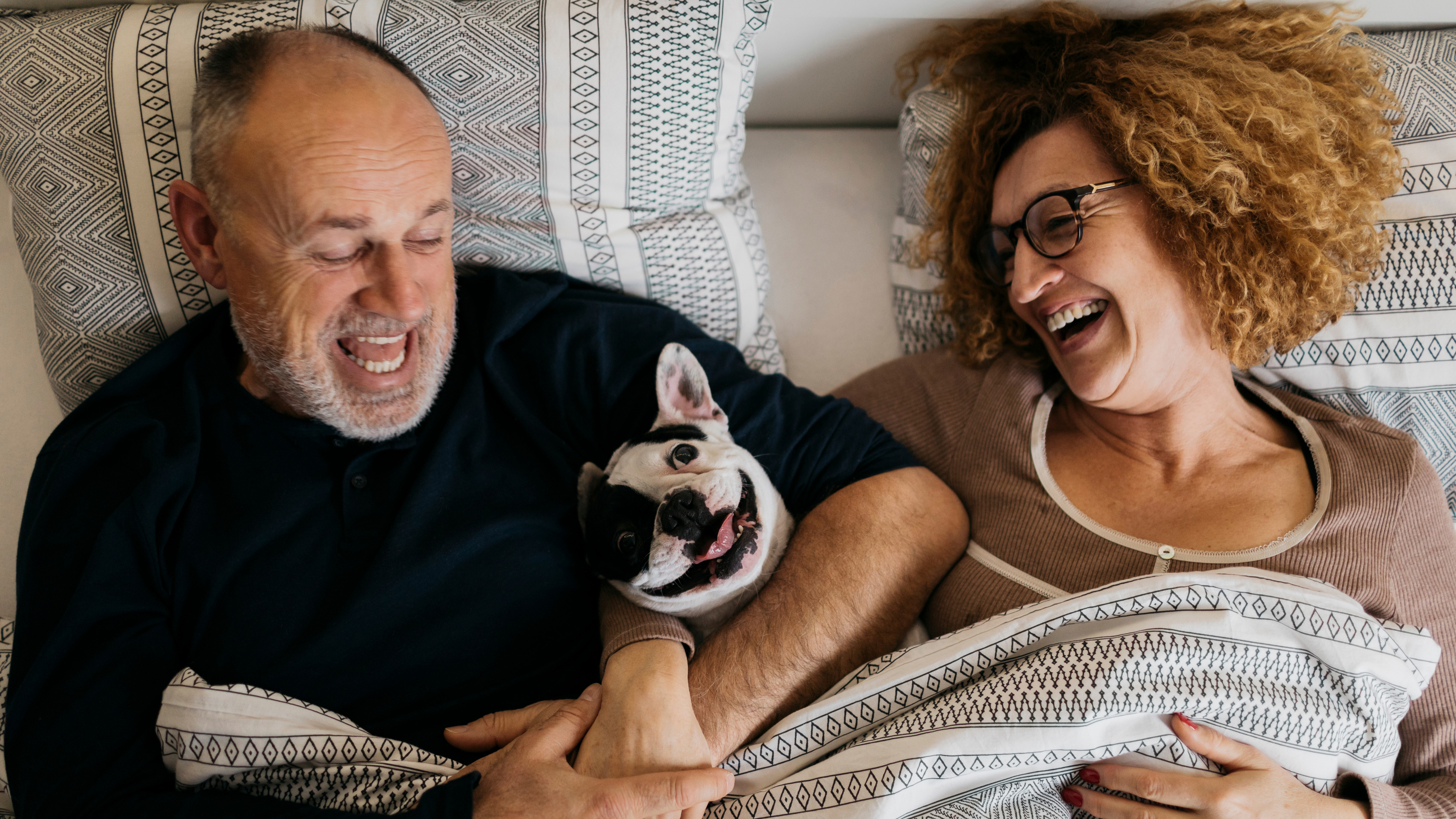 <p>Elderly couple in bed with dog.</p>