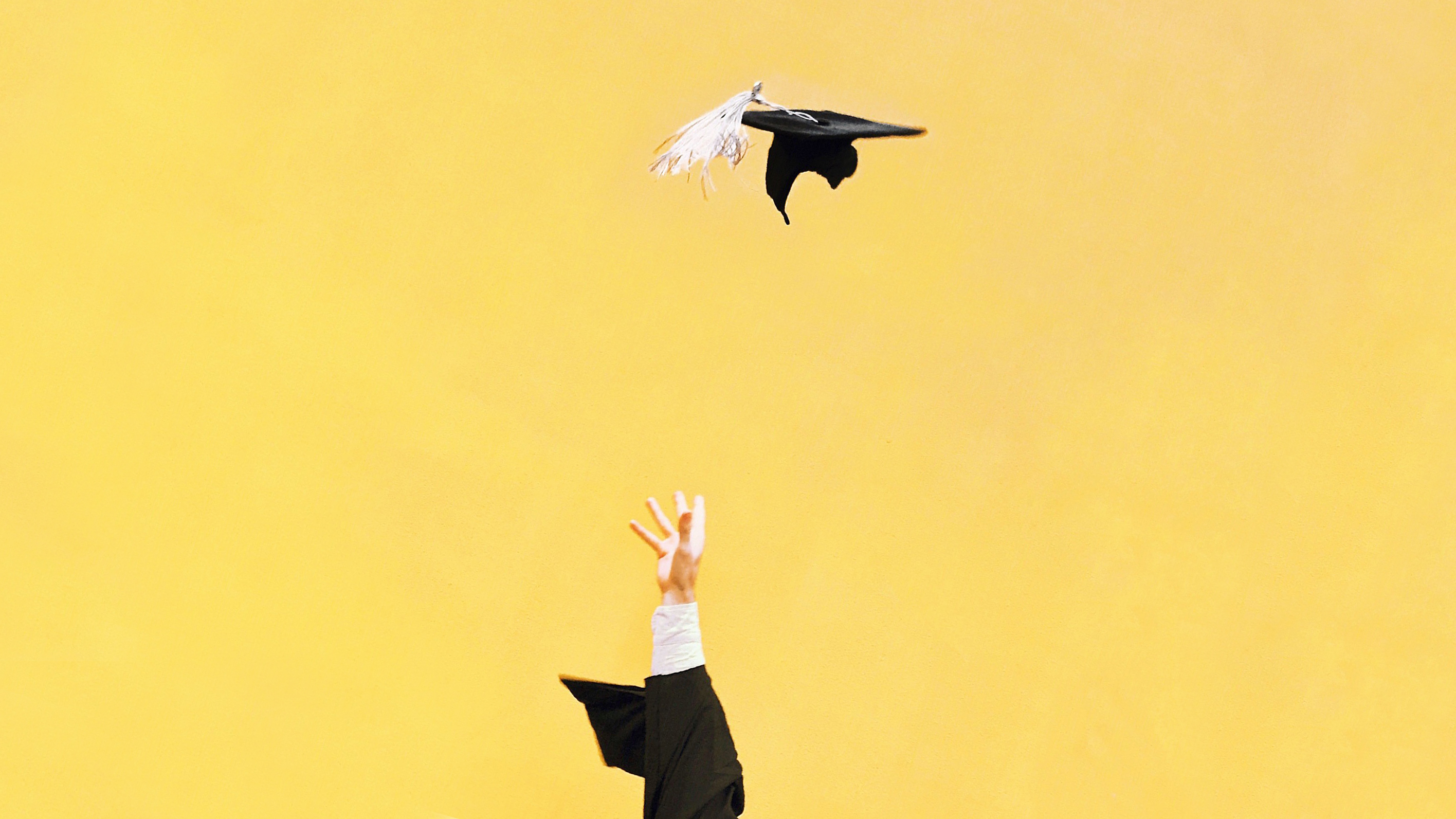 <p>Hand throwing mortarboard on yellow background.</p>