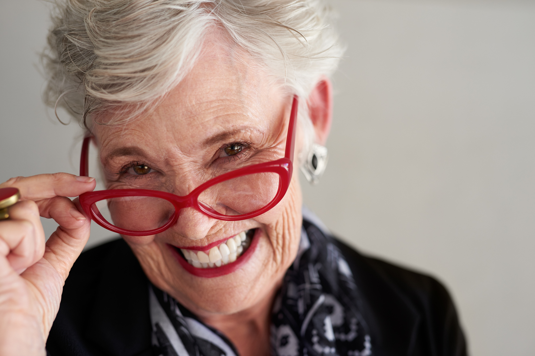 <p>Savvy Older Mature Woman posing for a a portrait with gray hair and red eyeglasses</p>